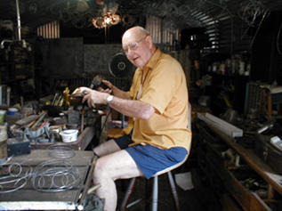 Woody Sitzer works in his backyard workshop, making frames for pine needle baskets.